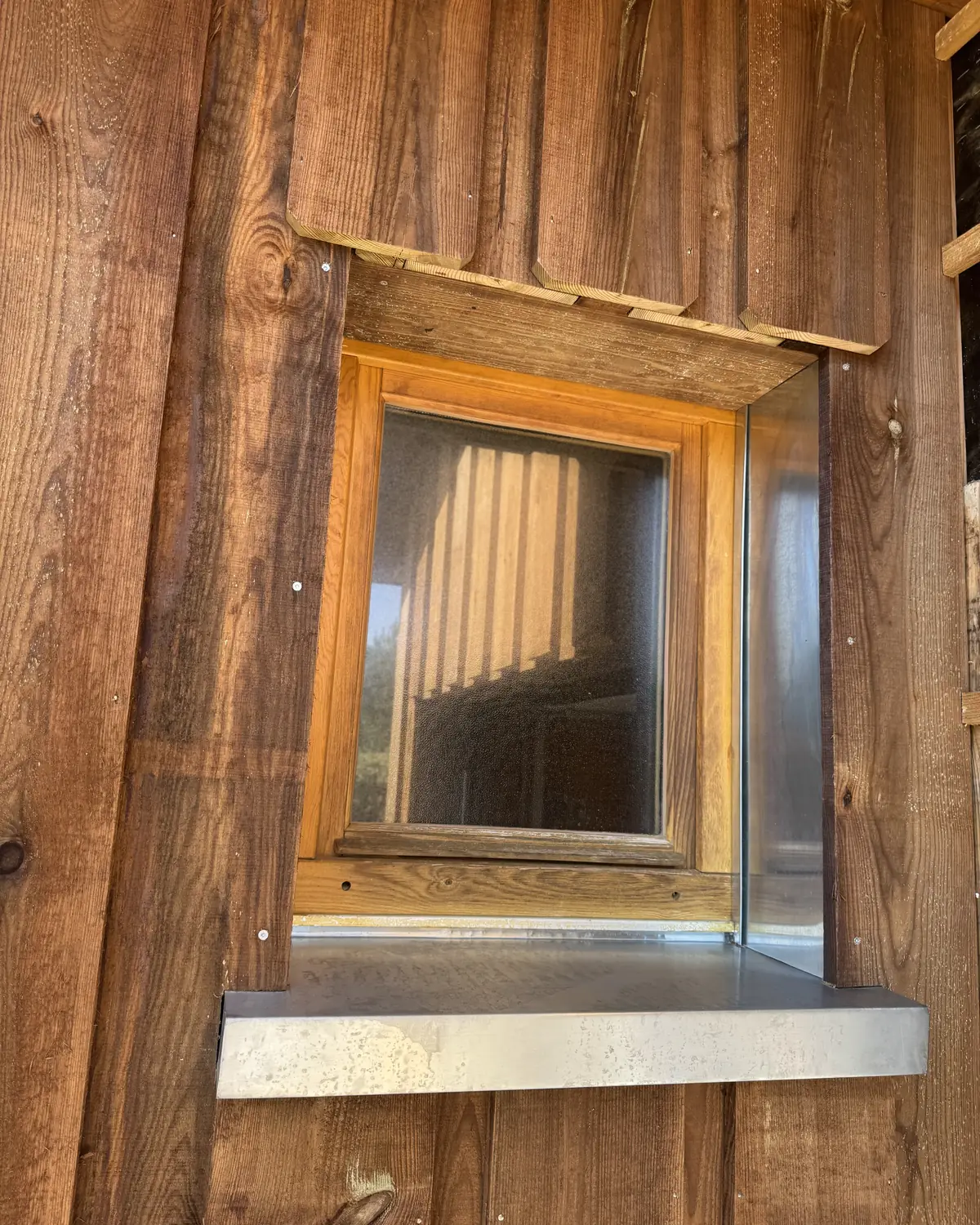 Fenêtre en bois avec appui en zinc dans un bardage bois
