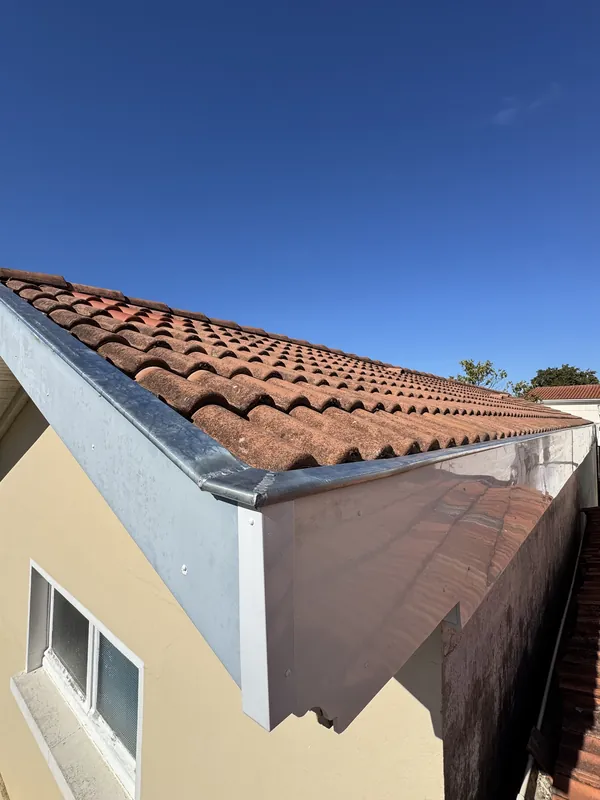 Bande de rive métallique le long d’un toit de tuiles canal, avec retour sur le pignon d’une maison